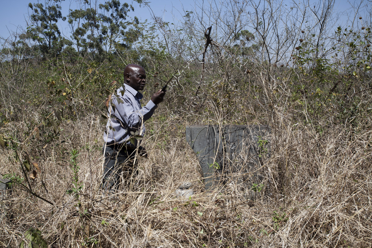 Eddy Baloye clears out the bushes that has grown over his father's grave on Syferfontein.